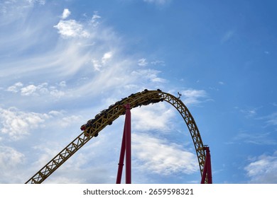 Experience the thrill of a roller coaster soaring under a vibrant sky with a breathtaking drop that intensifies the fun