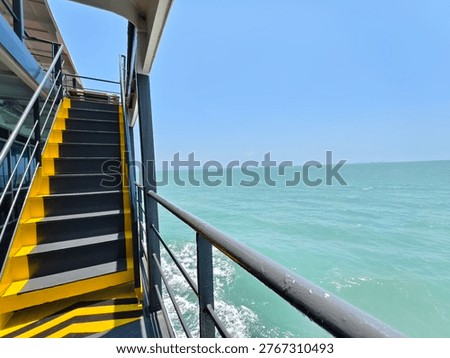 Experience the tranquility of the ocean from a ferry deck, with vibrant yellow stairs and endless blue waters.