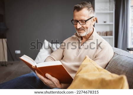 Experience the tranquility of reading with a wise and studious mature bearded man indoors