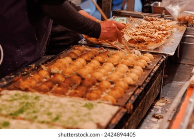 Experience the vibrant culture of Japan through this captivating image of Takoyaki, a popular street food, being prepared at a festival.