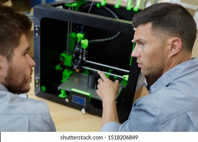 experienced architect showing apprentice 3d printer
