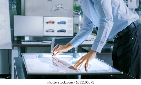 Experienced Automotive Designer Works With Digital Display Graphics Tablet Touschreen Table, Drawing Sketch of a New Car Prototype.
