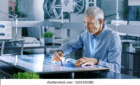 Experienced Automotive Designer Works With Digital Display Graphics Tablet Touschreen Table, Drawing Sketch of a New Car Prototype.