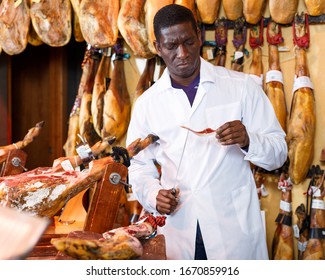 Experienced Butcher Shop Owner Checking Quality Of Jamon Before Sale

