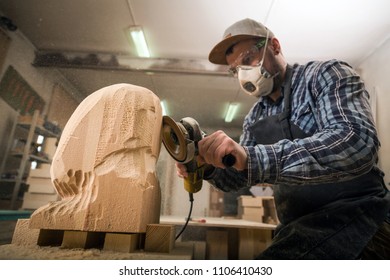 Experienced carpenter in work clothes and small buiness owner working in woodwork workshop, processes the board with an angle grinder on the table is a hammer and many tools  - Powered by Shutterstock