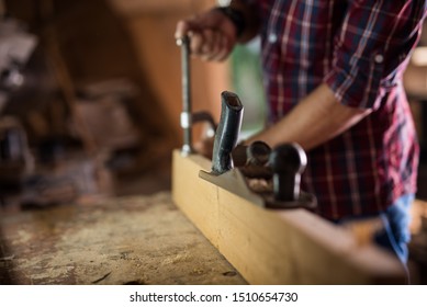 Experienced carpenter in work clothes and small business owner working in woodwork workshop, using sandpaper for polishing
