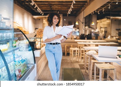 Erfahrener Kaukasaner-Manager der örtlichen Bäckerei, der mit Papierdokumenten arbeitet, die die Auftragsausführung analysieren, kleine weibliche Besitzer, die im gemütlichen Kaffeehaus arbeiten, verbessern die Geschäftsbeschäftigung im Haus