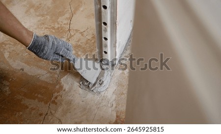 Experienced construction worker carefully applying concrete patching compound, meticulously filling and repairing visible crack on concrete floor surface