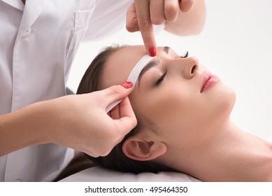 Experienced cosmetician pulling out brows