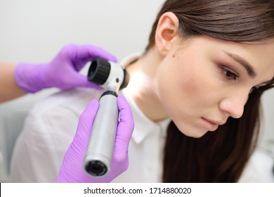 An experienced dermatologist examines the moles and nevi of a pretty young female patient with a Dermatoscope. Prevention of melanoma-skin cancer.
