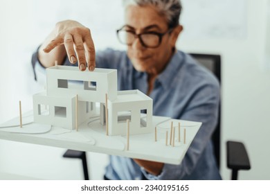 Experienced design architect analyzing a 3D model in her office, bringing her ideas of a sustainable building design to life. Senior professional taking on a house construction project in her office. - Powered by Shutterstock