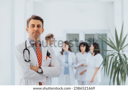Experienced doctor in a hospital, wearing lab coats. Confidently posing with folded arms. He smile and look at the camera.