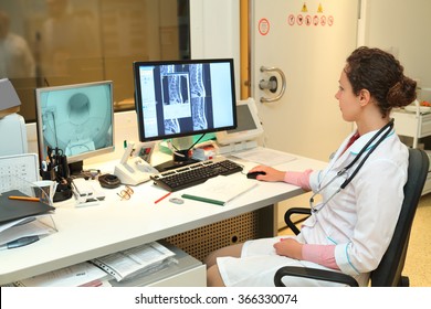 Experienced Doctor Looking At MRI Scan Of Lumbar Region On Monitor 