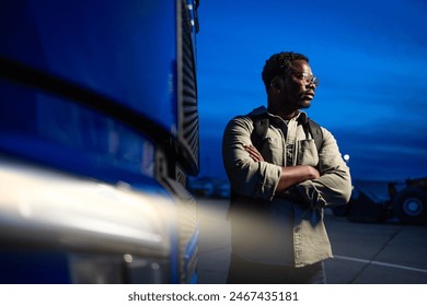 Experienced driver standing by his truck ready for night drive.