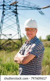 Experienced engineer with white hard hat under the power lines. Engineer work at an electrical substation.
