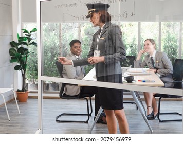 Experienced Female Flight Instructor Focus On Writing Lessons On Glass Board. Cheerful Black Man And Woman Students Happy Attentively Learning In The Academic Classroom At Aviation Education Center.