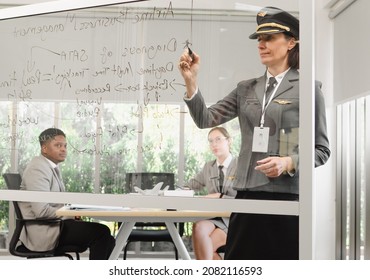 Experienced female flight instructor focus on writing lessons on glass board. Black man and woman co-pilot students are attentively learning in the academic classroom at aviation education center. - Powered by Shutterstock