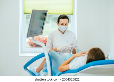 Experienced female gynecologist in lab coat, face mask and gloves holding medical vaginal speculum for examining patient. Young woman lying on gynecological chair during check up. - Shutterstock ID 2054523821