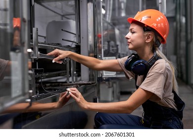 Experienced female repairing broken equipment in factory using wrench, woman in uniform and hardhat is concentrated on work, looking confident and professional. engineer woman is preparing for work