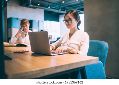 Experienced Female Secretary In Optical Eyewear Editing Web Documents During Working Time In Office Interior, Skilled Employer Reading News While Booking Webinar Via Application On Netbook Technology