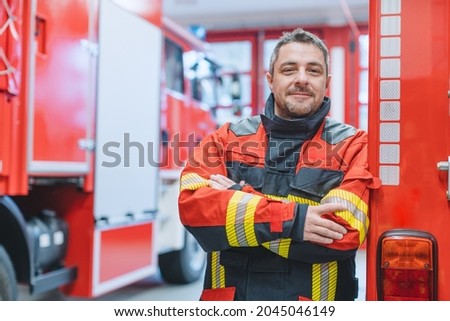 Experienced fire fighter man standing in front of fire truck