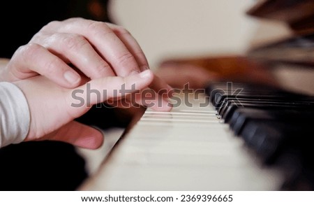 Experienced hand of the old music teacher helps the child student. Experienced master piano hand helps the student, close-up.