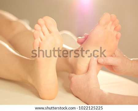 Experienced hands give a foot massage to a young womans foot