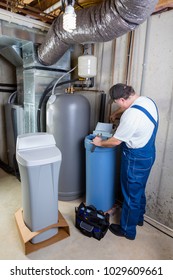 Experienced Home Installer Fixing Issues Encountered On A New Water Softener Tank That He Is Installing Using His Tools In A Utility Room In A Basement