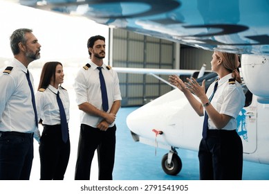 Experienced instructor leading a training session for a group of aspiring pilots next to a small aircraft in a hangar