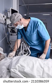 Experienced Male Doctor Putting Stethoscope To Senior Patient, Checking The Heartbeat. At Nursing Hospital Ward. Elderly Male Lying On Bed With Injections, Under A Dropper, In Hospital