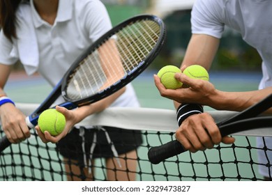 Experienced male tennis coach giving instructions to his student, standing by net at the outdoor tennis court - Powered by Shutterstock