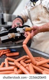 Experienced Male Worker Makes And Fills Delicious Hot Dogs In Fresh Meat Processing Plant. Industrial Slaughterhouse Worker Job. Pneumatic Hot Dog Filler Machine. Food Industry Business Concept.