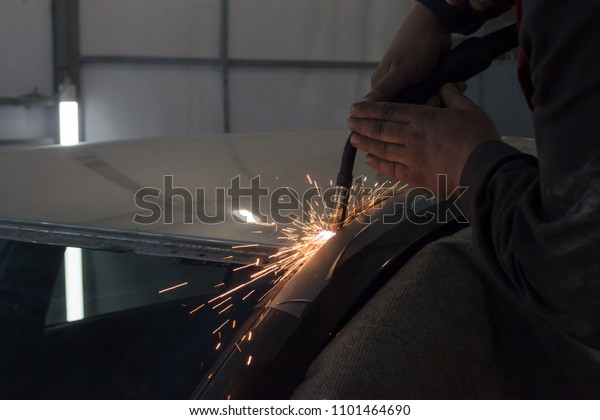 Experienced man performs work\
on body repair car with a welding machine. Repair of the roof of\
the vehicle.