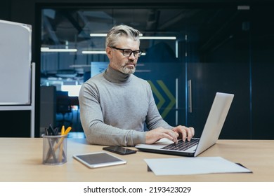 Experienced And Mature Successful Businessman Focused And Serious Man Working Inside Office Building At Laptop, Investor In Glasses And Casual Clothes