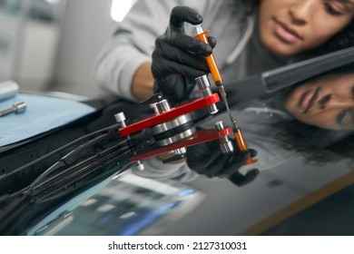 Experienced mechanic repairing cracked windshield on client vehicle - Shutterstock ID 2127310031