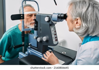 Experienced Optometrist Doing Sight Test For Senior Man At Modern Ophthalmology Clinic. Eye Exam And Vision Diagnostic