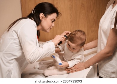 Experienced otolaryngologist examining eardrum of little baby - Powered by Shutterstock