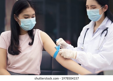 Experienced phlebotomist preparing tourniquet a woman for blood draw