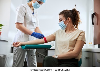 Experienced phlebotomist preparing a woman for blood draw