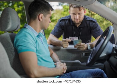 Experienced policeman is checking young man's driving licence