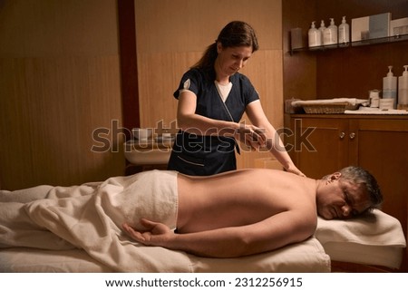 Experienced practitioner preparing customer for ayurvedic massage session