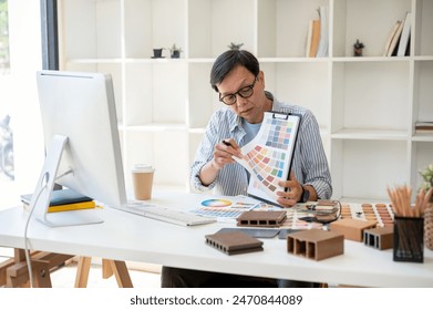 An experienced and professional senior Asian male interior designer or architect is having an online meeting with his team and client, presenting and showing the color swatch sample for the design. - Powered by Shutterstock