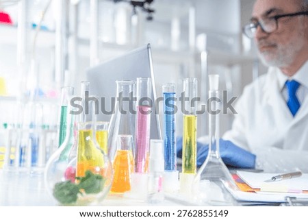 Experienced professor recording experimental data on a laptop while working in a laboratory. Concept of digital research documentation, data analysis, academic standards and modern scientific workflow.