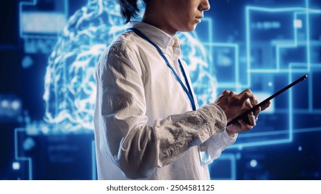 Experienced programmer in data center uses artificial intelligence computing simulating human brain thought processes. Overseeing supervisor works on tablet with AI machine learning algorithms