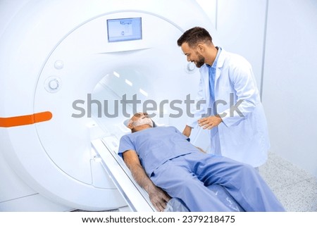 Experienced radiologist encouraging senior patient before MRI or CT scanning procedure in hospital.