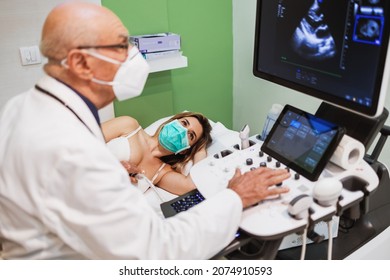 Experienced senior doctor performs a cardiac examination on a young female patient. He is using cardiology scanner. Medicine and modern technology concept.