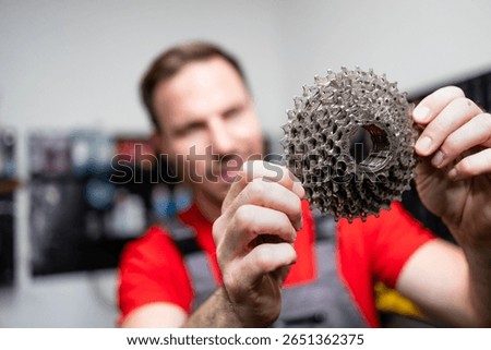 Experienced serviceman checking bicycle gears in workshop. Preparing bike for the season.