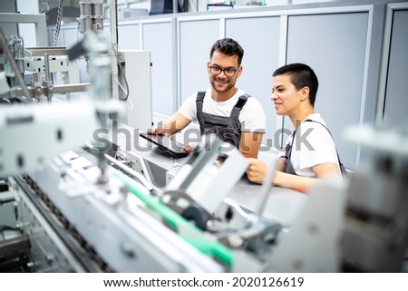 Experienced serviceman controlling process and servicing modern industrial manufacturing machine in production factory.