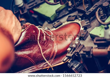 Experienced shoemaker using a special machine for putting shoes on the mold, in the handmade footwear industry. Selective focus and small depth of field.