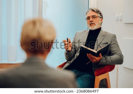 An experienced shrink is sitting in a doctor's office with a client and giving a supportive talk and advising her during a session. A psychotherapist is giving support and advice to a senior woman.